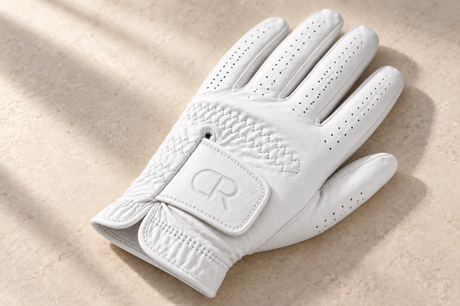 White golf glove with the Calder Row CR monogram debossed on the closure strap